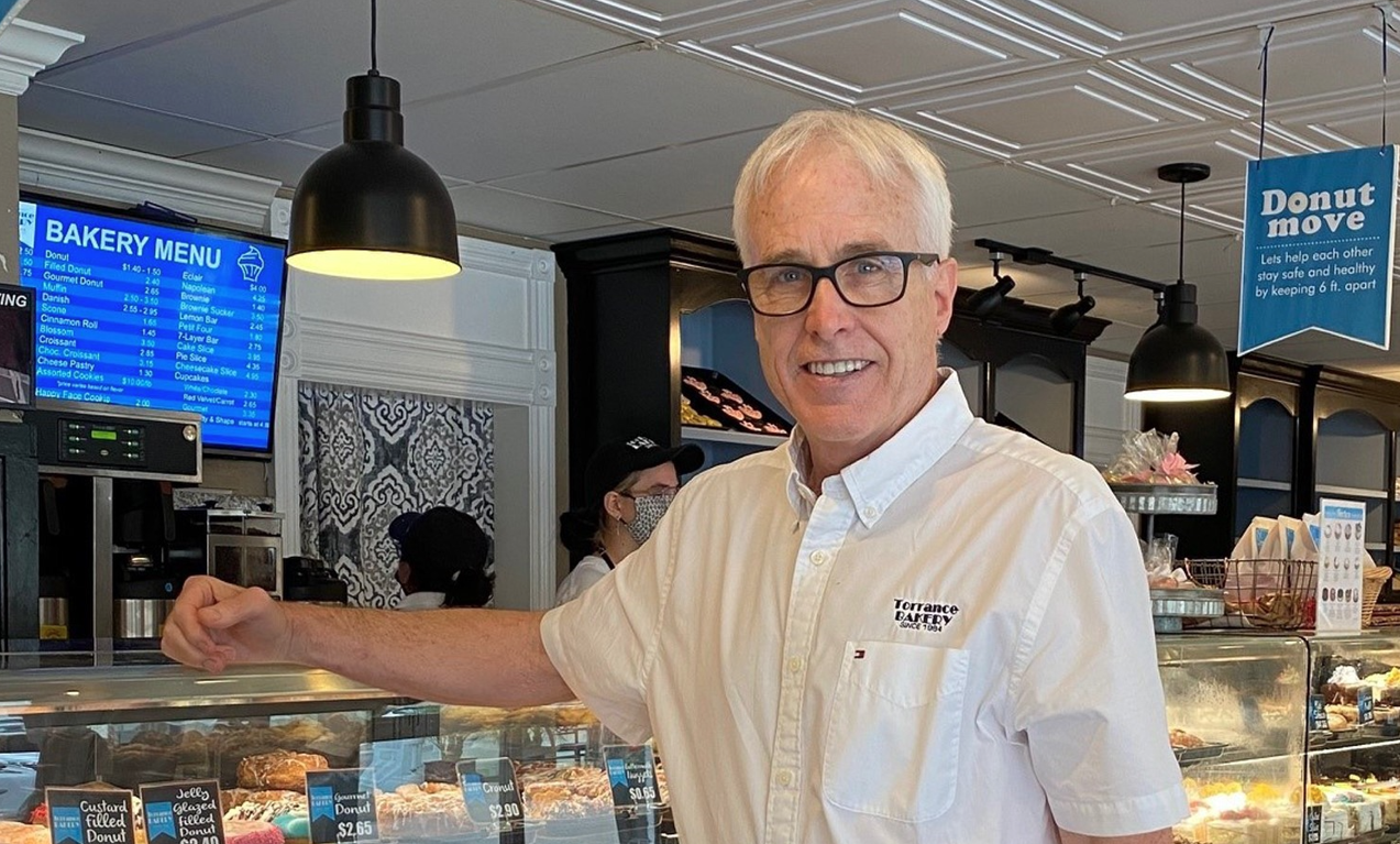 Torrance Bakery owner Kirk Rossberg standing in front of a donut counter