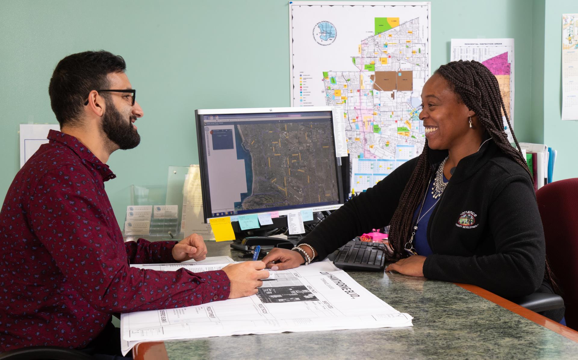 Torrance employee smiling looking over building plans with a business owner